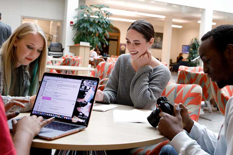 Three students work at a table in the central commons of Franklin Hall.