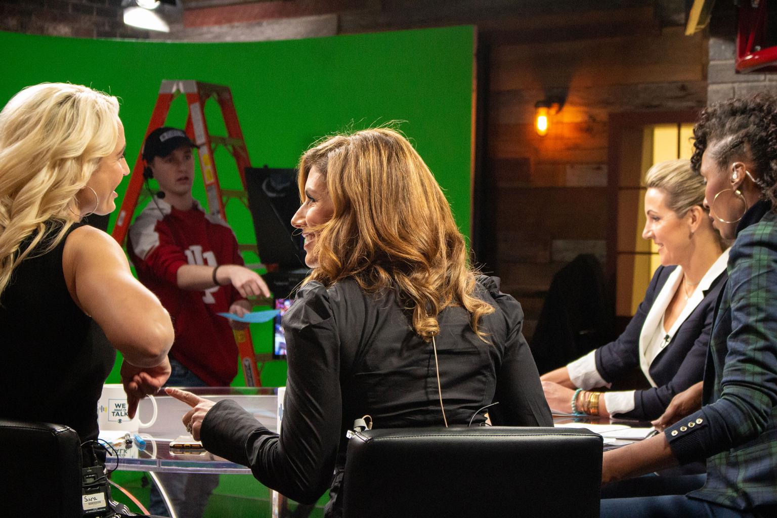 Four women sit around the anchor table in Beckley Studio preparing for a show.
