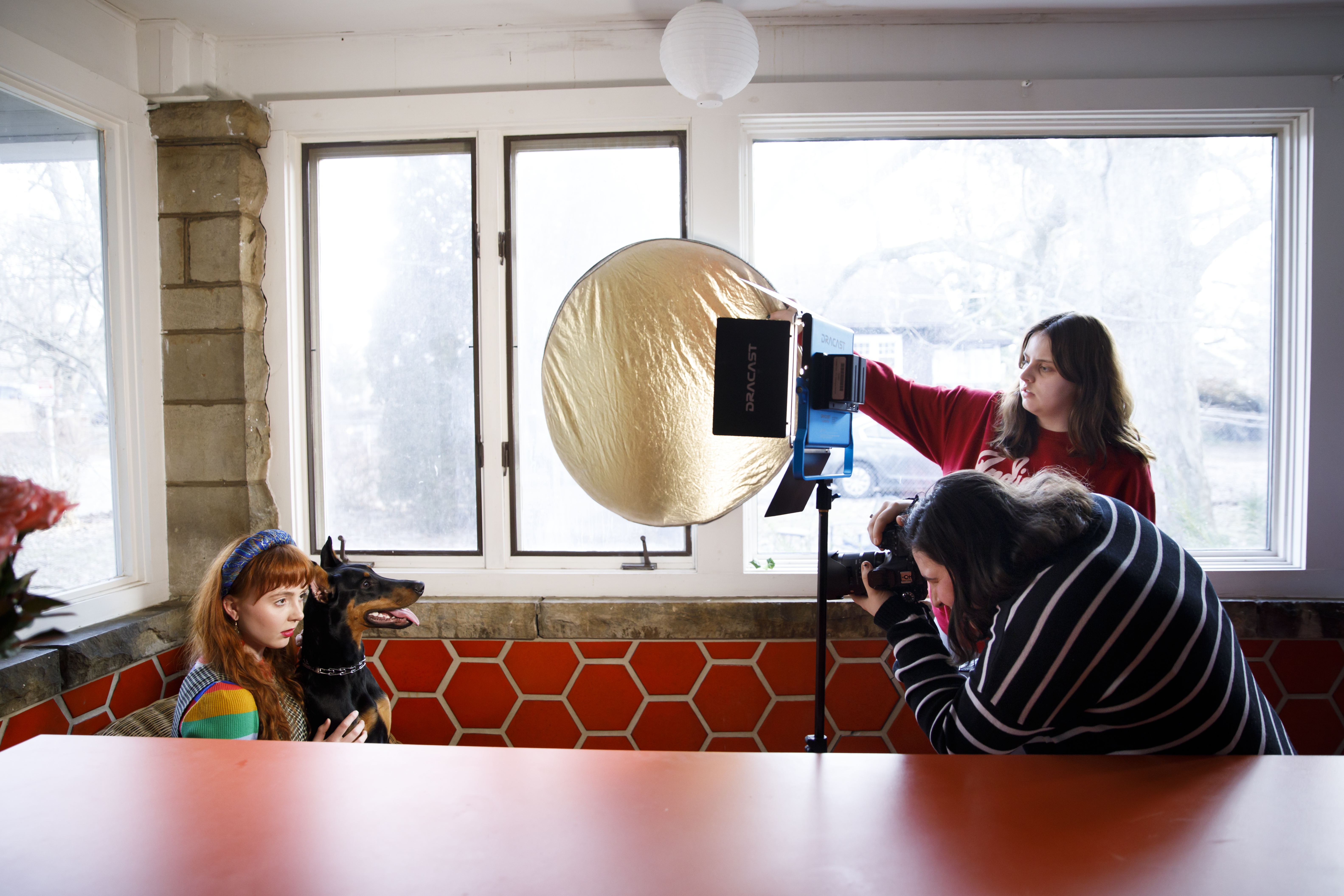 A model poses with a dog while two students take photos for Season Magazine.