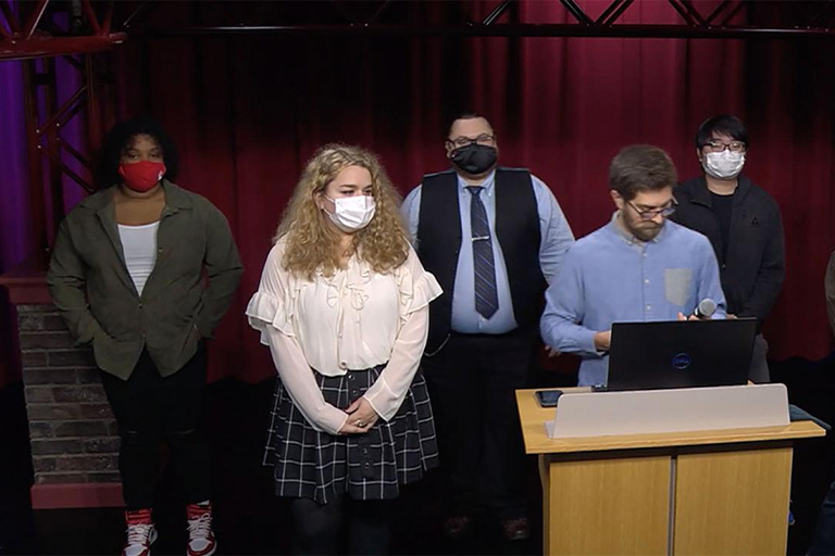 Students stand at a podium during the game design Shark Tank tournament.