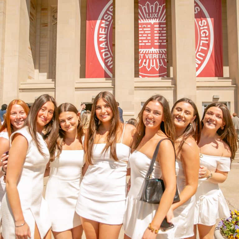 Group of graduates stand on the steps of the IU Auditorium. 