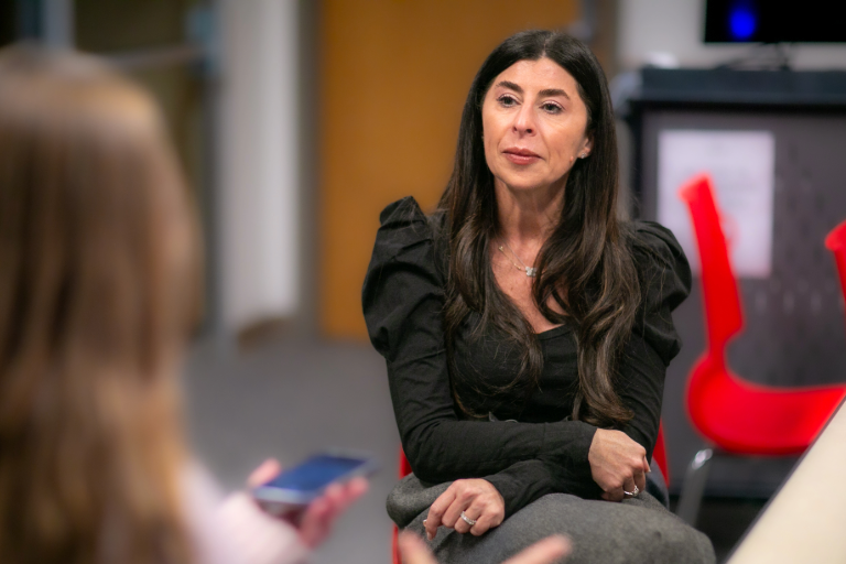 Woman watches a person speak.